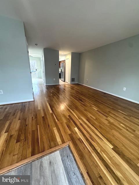 unfurnished living room featuring baseboards and wood finished floors