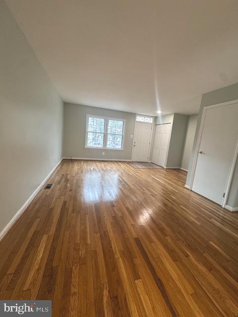 unfurnished living room with visible vents, baseboards, and wood finished floors