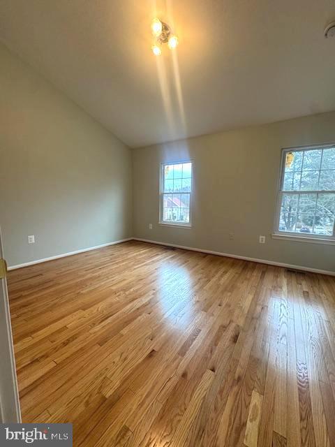 unfurnished room with vaulted ceiling, baseboards, and wood finished floors