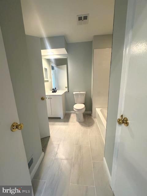 bathroom featuring baseboards, visible vents, toilet, a tub, and vanity