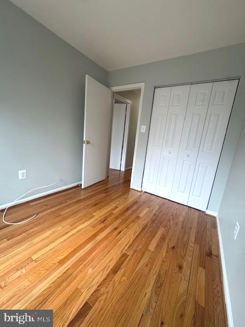 unfurnished bedroom featuring a closet, baseboards, and wood finished floors