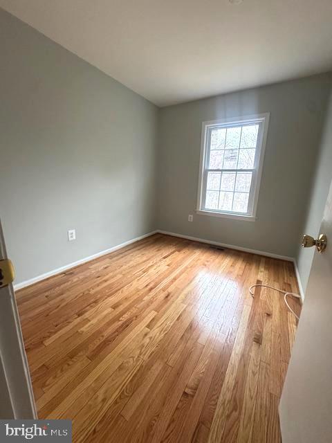 empty room featuring baseboards and hardwood / wood-style floors