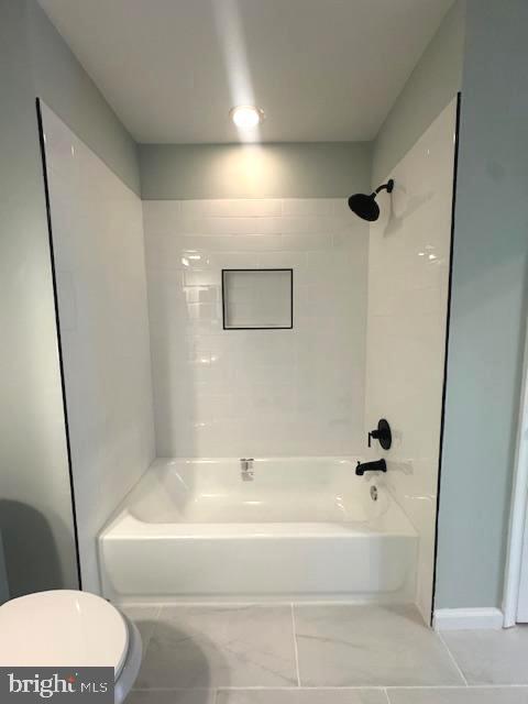 bathroom featuring shower / bathing tub combination and toilet