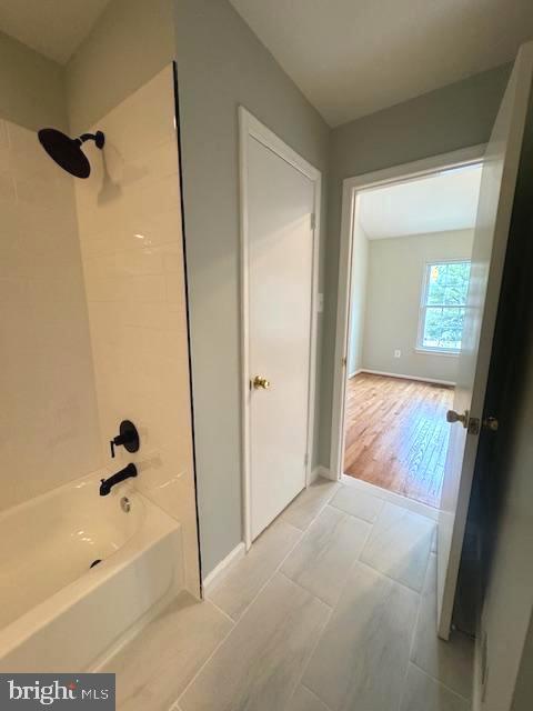 full bath featuring bathing tub / shower combination, baseboards, and wood finished floors