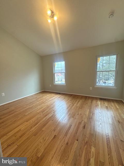 unfurnished room featuring lofted ceiling, wood finished floors, and baseboards