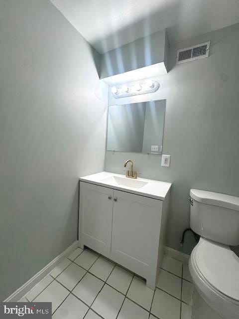 bathroom with toilet, vanity, baseboards, visible vents, and tile patterned floors