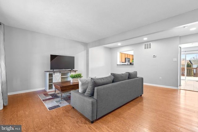 living room with recessed lighting, baseboards, visible vents, and light wood finished floors