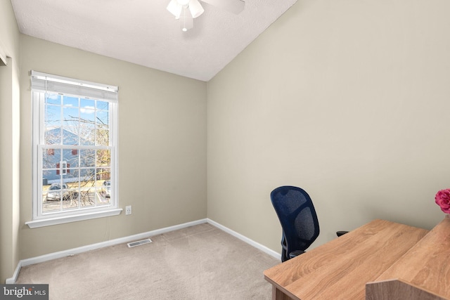 carpeted home office with a ceiling fan, baseboards, visible vents, vaulted ceiling, and a textured ceiling