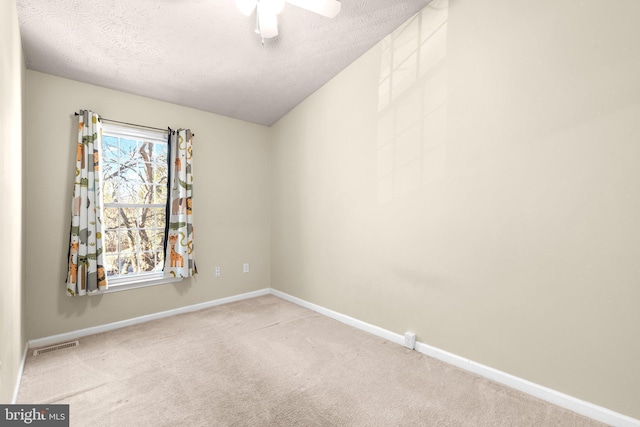 empty room with carpet, visible vents, baseboards, ceiling fan, and a textured ceiling