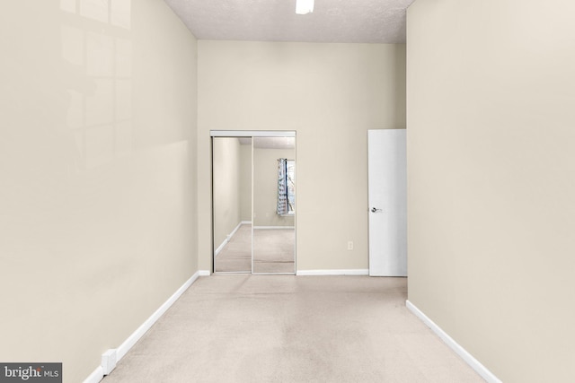 hallway with carpet flooring, a textured ceiling, and baseboards