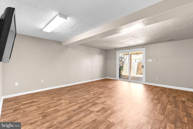 spare room featuring visible vents, baseboards, a textured ceiling, and wood finished floors