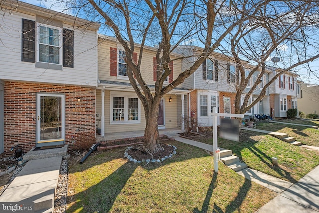 multi unit property featuring a front yard and brick siding