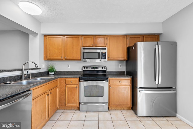 kitchen with a sink, stainless steel appliances, brown cabinets, and dark countertops