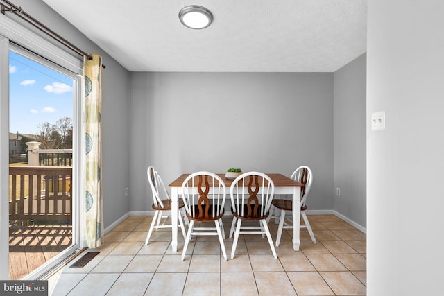 dining room with visible vents, baseboards, a textured ceiling, and light tile patterned flooring