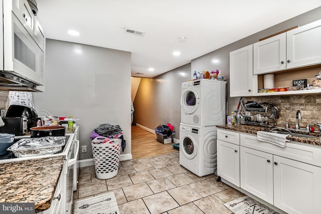 laundry room featuring laundry area, visible vents, stacked washer / dryer, a sink, and recessed lighting