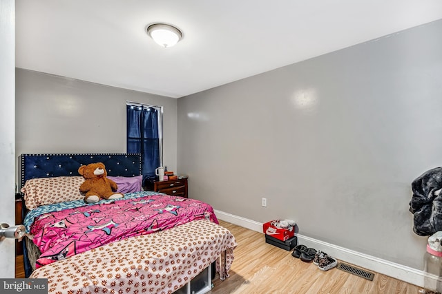 bedroom with wood finished floors, visible vents, and baseboards