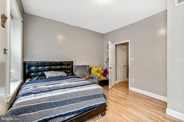 bedroom featuring visible vents, baseboards, and wood finished floors