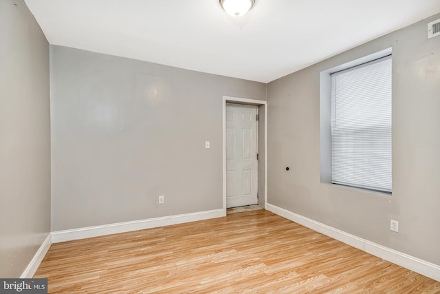 empty room with light wood-type flooring, visible vents, and baseboards