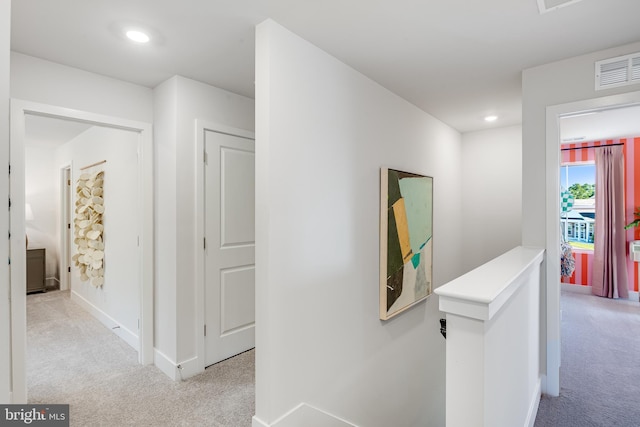 corridor with visible vents, baseboards, light colored carpet, an upstairs landing, and recessed lighting