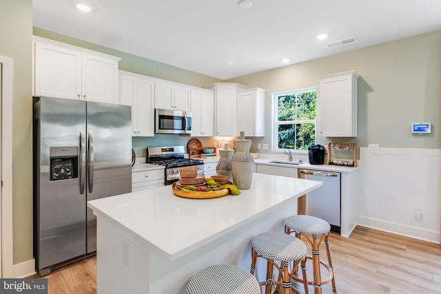 kitchen with light wood finished floors, visible vents, appliances with stainless steel finishes, white cabinetry, and a sink