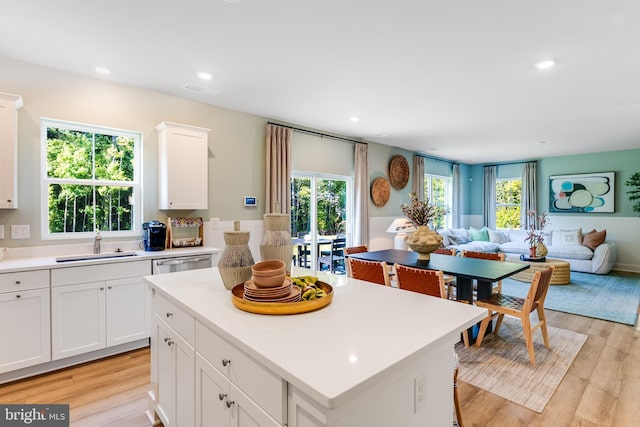 kitchen featuring stainless steel dishwasher, light wood-style floors, open floor plan, and a sink