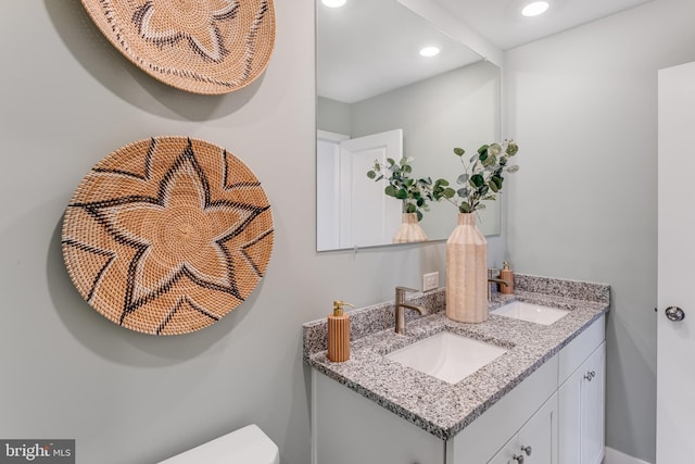 bathroom with recessed lighting, a sink, toilet, and double vanity