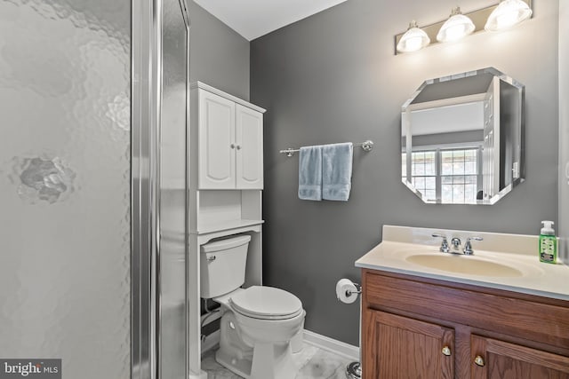 bathroom featuring toilet, marble finish floor, baseboards, and vanity