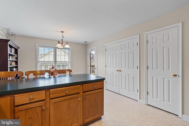 kitchen with dark countertops, light floors, brown cabinets, and pendant lighting