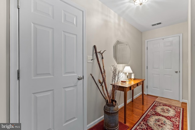 foyer entrance with wood finished floors, visible vents, and baseboards