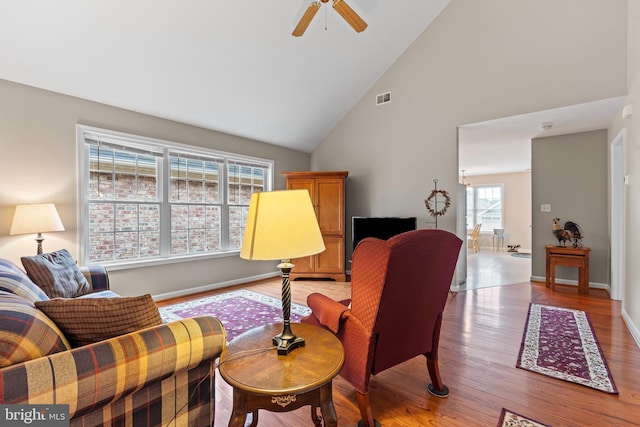 interior space with high vaulted ceiling, a ceiling fan, visible vents, baseboards, and light wood finished floors