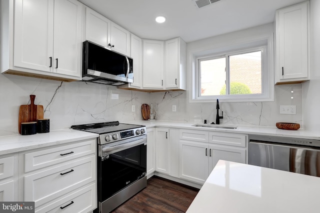 kitchen featuring backsplash, appliances with stainless steel finishes, white cabinets, and a sink