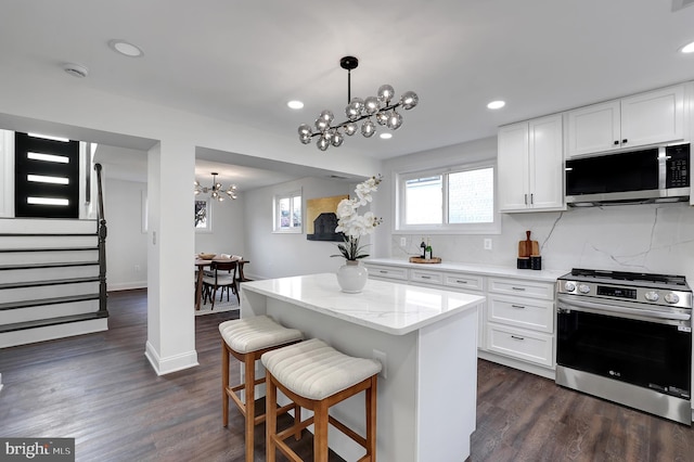 kitchen featuring dark wood-style floors, appliances with stainless steel finishes, white cabinetry, and a notable chandelier