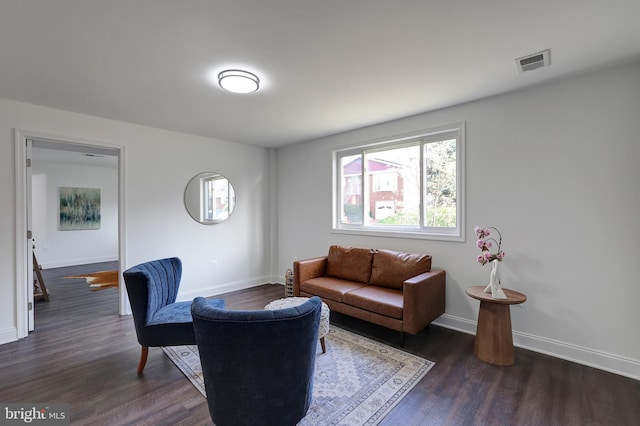 living area with dark wood finished floors, visible vents, and baseboards