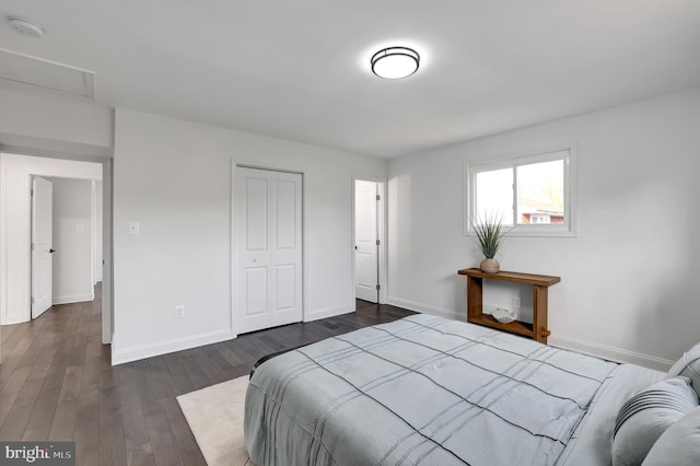 bedroom with attic access, baseboards, dark wood finished floors, and a closet