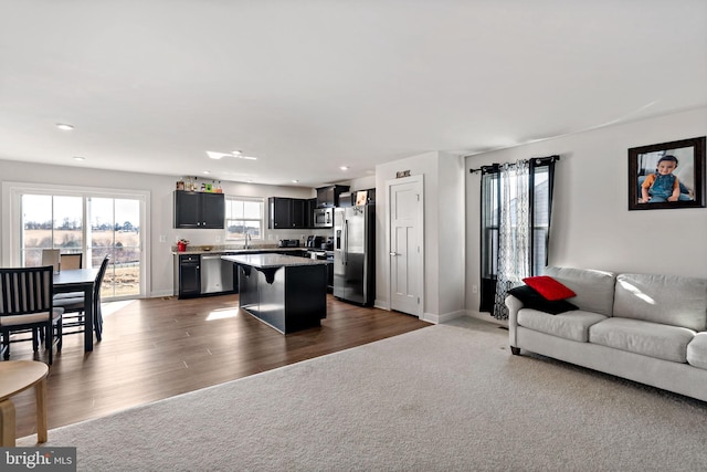 living area with dark colored carpet, recessed lighting, dark wood finished floors, and baseboards