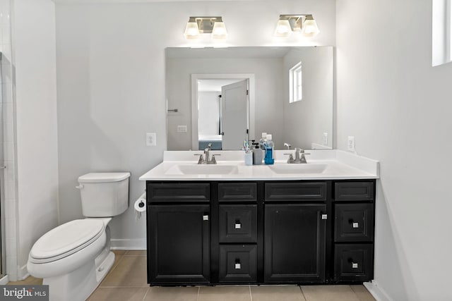 bathroom with baseboards, a sink, toilet, and double vanity