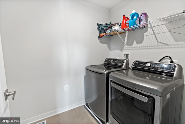 washroom featuring tile patterned flooring, laundry area, baseboards, and separate washer and dryer