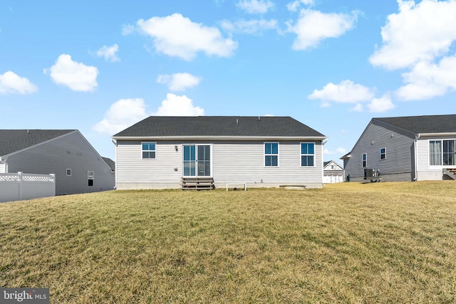 rear view of house featuring entry steps, fence, and a yard