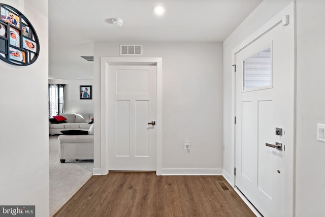 foyer featuring visible vents, baseboards, and wood finished floors