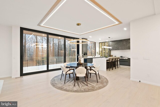 dining area with baseboards, light wood finished floors, visible vents, and floor to ceiling windows