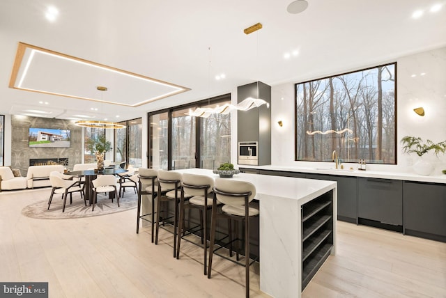 kitchen with gray cabinetry, a sink, a high end fireplace, light countertops, and modern cabinets