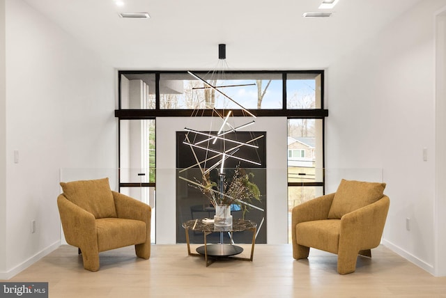 sitting room with a wall of windows, wood finished floors, and baseboards