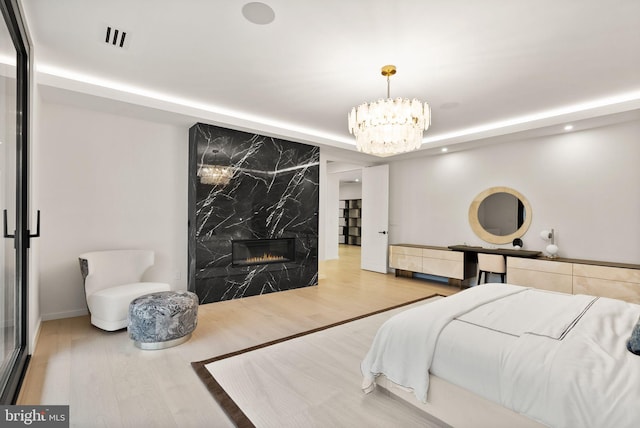 bedroom with visible vents, a premium fireplace, wood finished floors, a notable chandelier, and recessed lighting