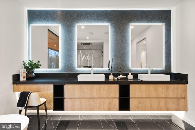 bathroom featuring double vanity, walk in shower, and a sink