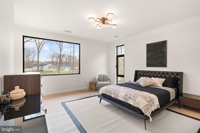 bedroom featuring visible vents, light wood-style flooring, and baseboards