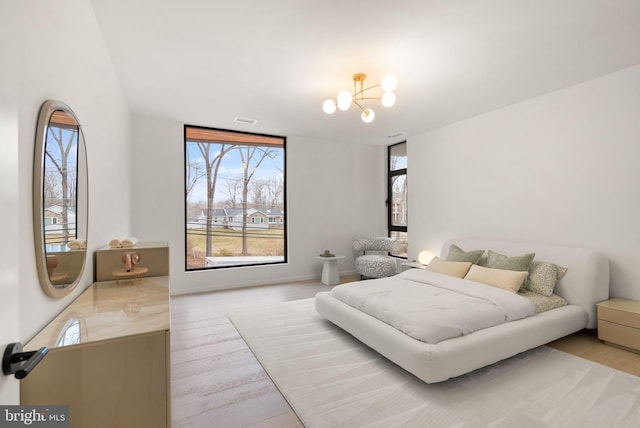 bedroom featuring visible vents, a chandelier, and wood finished floors