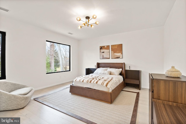 bedroom featuring baseboards, visible vents, a chandelier, and wood finished floors