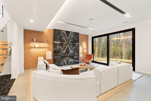 living area with wooden walls, visible vents, an accent wall, a fireplace, and recessed lighting