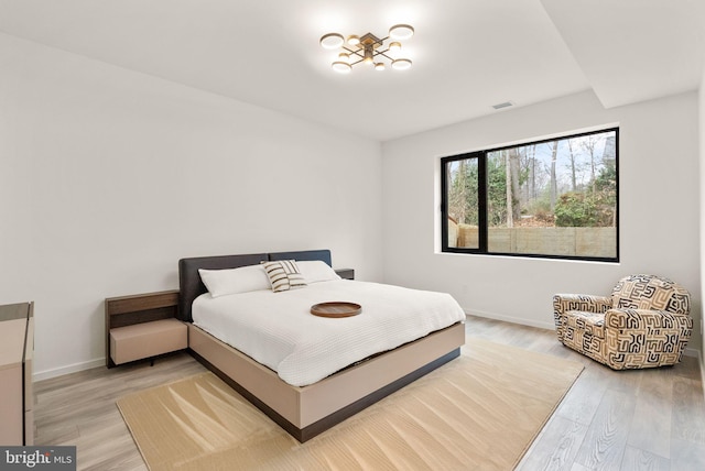 bedroom featuring light wood finished floors, baseboards, and visible vents