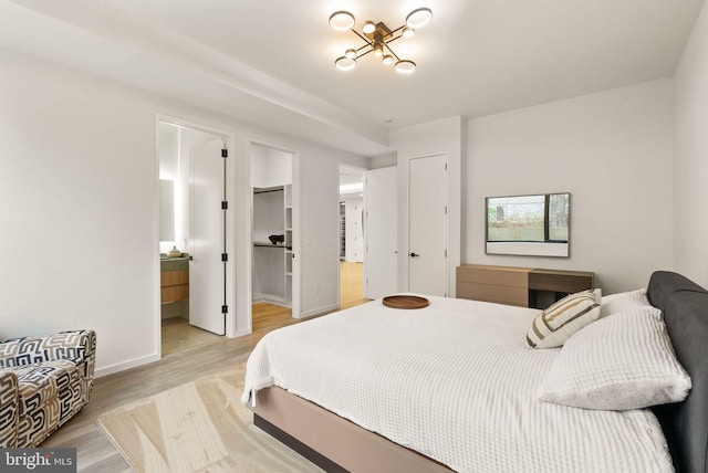 bedroom with light wood-style floors, a closet, a spacious closet, and baseboards